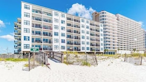 A multi-story hotel with a beachside location, featuring balconies and a clear view of the ocean.