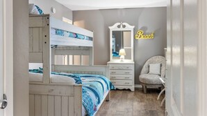 A bedroom with bunk beds, a dresser, a chair, and a mirror.