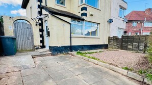 En tvåvånings bostadsbyggnad med en uppfart belagd med plattor och en grind vid ingången.