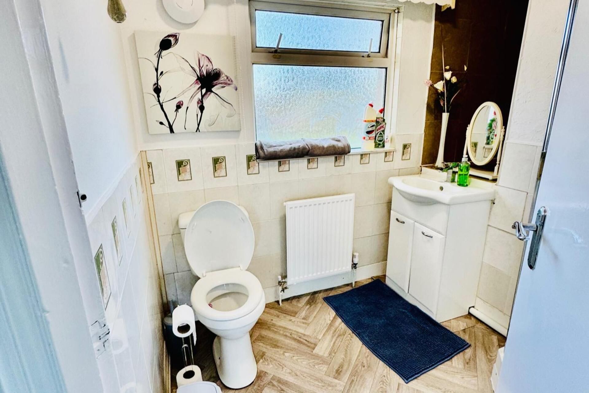 Un baño pequeño con inodoro, lavamanos, espejo y ventana.