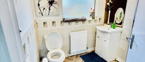 Un baño pequeño con inodoro, lavamanos, espejo y ventana.