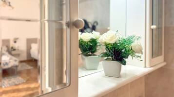 Une salle de bain avec un miroir, un lavabo et deux plantes en pot sur le comptoir.