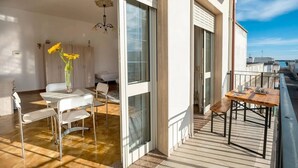 A modern apartment with a balcony, a dining area with a table and chairs, and a room with a bed and a vase of sunflowers. - Room-abissi Room Vista Mare B&b Controve (Porto Cesareo)