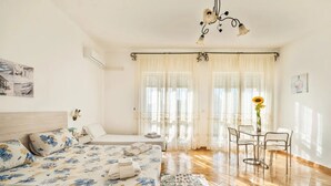 A hotel room with a bed, a small table with chairs, a chandelier, and a window with curtains. - Room-abissi Room Vista Mare B&b Controve (Porto Cesareo)