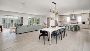 A spacious living area with a large sofa, a dining table with chairs, and a kitchen area with bar stools.