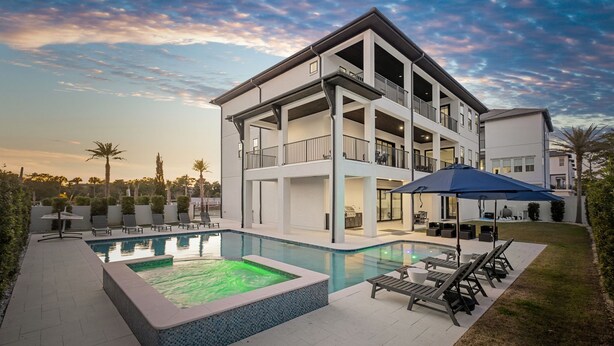 A modern two-story house with a swimming pool, outdoor seating, and a covered patio area.