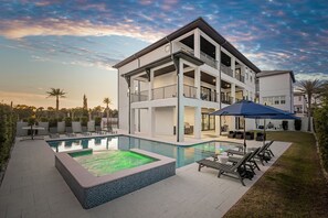 A modern two-story house with a swimming pool, outdoor seating, and a covered patio area. - Emerald Palace | Private Pool/Spa | Indoor Theater | Game Room (Santa Rosa Beach)