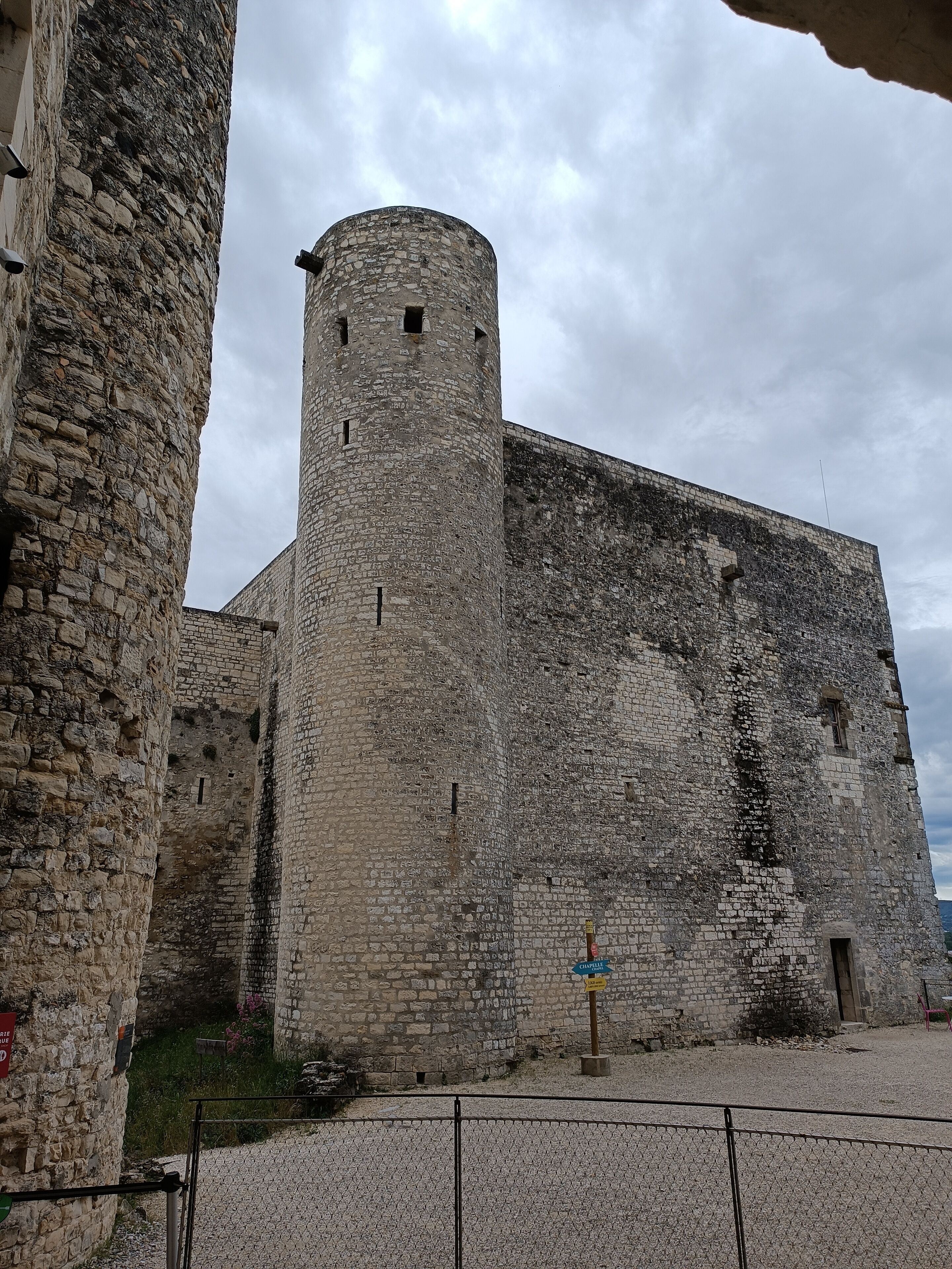 A historic stone building with a prominent tower and a fortified wall.