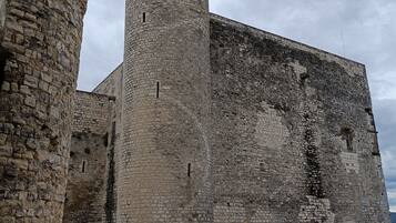 A historic stone building with a prominent tower and a fortified wall.