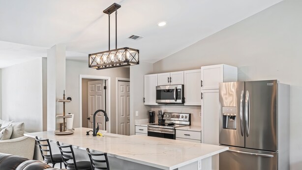 A modern kitchen with a central island, stainless steel appliances, and a pendant light. - Coastal Escape in Gulf Breeze! 3BR w/ Pool, Putting Green & Fire Pit (Gulf Breeze)