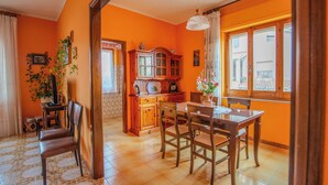 A dining area with a wooden table and chairs, a cabinet with glass doors, and a window with curtains. - Villa Corsica (Samatzai)