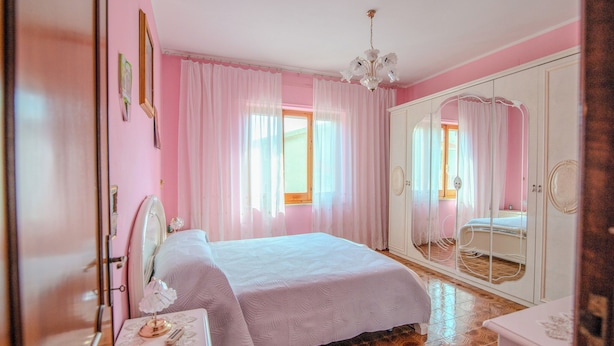 A bedroom with a bed, a bedside table, a mirror, a wardrobe, and a chandelier. - Villa Corsica (Samatzai)