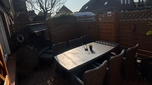Un patio con mesa y sillas, una parrilla y una valla de madera.