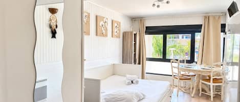 Una habitación de hotel con cama, una mesa de comedor con sillas, un espejo y obras de arte en la pared.
