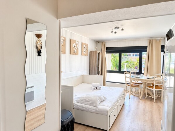 Ein Hotelzimmer mit Bett, Esstisch mit Stühlen, Spiegel und Bildern an der Wand.