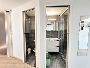 A modern bathroom with a shower, toilet, and sink.