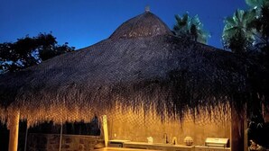 An outdoor dining area with a thatched-roof structure, a stone wall, and a grill station. - Casitas with pool & jacuzzi (Todos Santos)