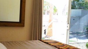 A hotel room with a bed, a window with curtains, and a view of the outside. - Casitas with pool & jacuzzi (Todos Santos)