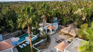 Ein Resort mit Pool, Sitzgelegenheiten im Freien und einem strohgedeckten Gebäude.