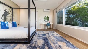 A modern bedroom with a four-poster bed, a desk, and a large window.