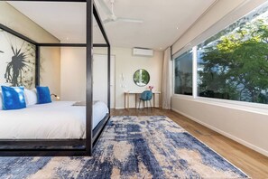 Une chambre à coucher moderne avec un lit à baldaquin, un bureau et une grande fenêtre.