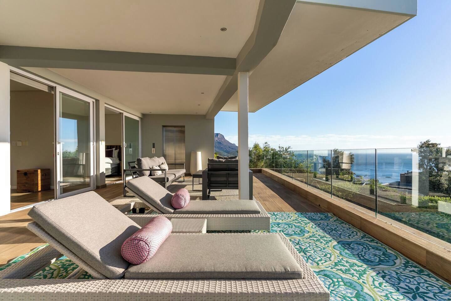A modern outdoor lounge area with a pool, seating, and a view of the sea.
