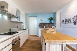 A modern kitchen with a wooden island, stainless steel appliances, and a potted plant.