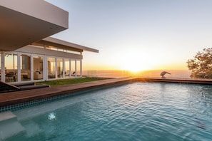 A modern building with a pool and a sunset view.