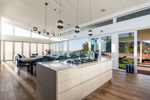 A modern kitchen with a central island, large windows, and a view of the outdoors.