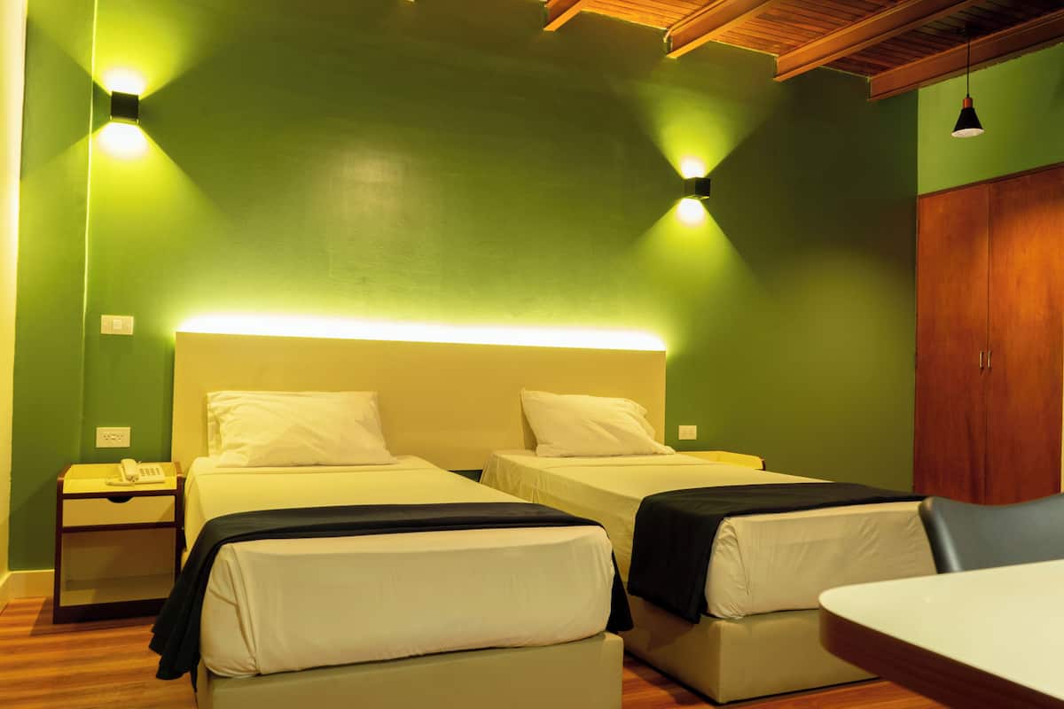 Een kamer met twee bedden, een houten nachtkastje met een telefoon en een tafel met een stoel.