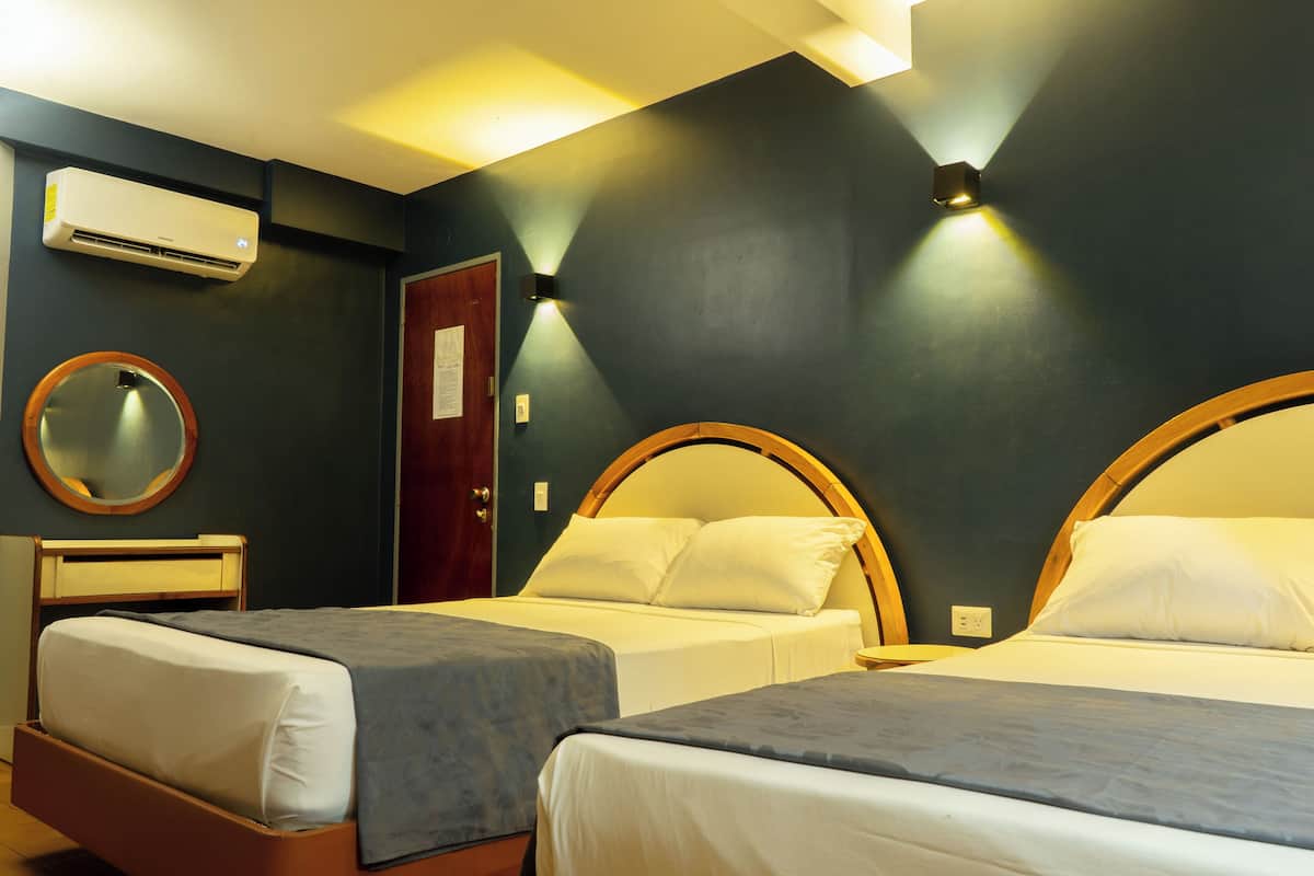 Een hotelkamer met twee bedden, een ronde spiegel, een airconditioningsunit en een deur met een bericht.