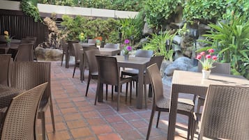 Eine Terrasse im Freien mit Korbmöbeln und Blumentöpfen.