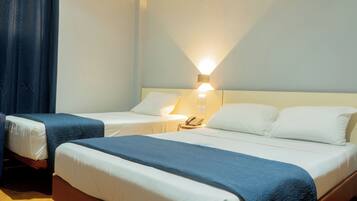 Une chambre d’hôtel avec deux lits, une table de chevet avec un téléphone et une lampe fixée au mur.