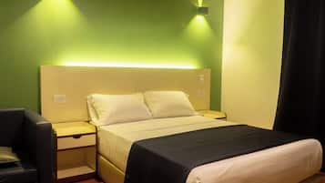 Una habitación de hotel con una cama, mesitas de noche, una silla y una mesita auxiliar.