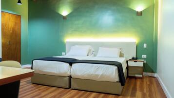A room with a double bed, bedside tables, a desk, and a chair.
