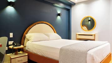 A neatly arranged bedroom with a bed, bedside table, and a mirror.