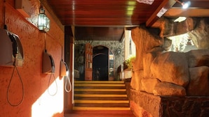 A hallway with stone walls, a wooden ceiling, and a staircase leading to a dark doorway. - Hotel El Arroyo (Caracas)