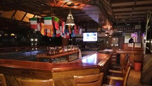 A bar area with wooden chairs, a bar counter, and a television screen. - Hotel El Arroyo (Caracas)