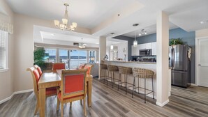 A spacious kitchen with a dining area, wooden flooring, and a view to the outside. - Harbour Towne 202 - Expansive main channel views! (Lake Ozark)