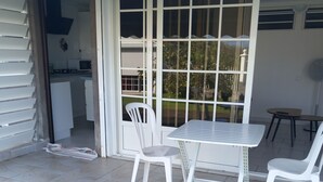 A patio area with a table and chairs, a view of the backyard, and a sliding glass door leading to a kitchen. - Source bis sea and hot water (Bouillante)