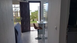 A narrow hallway with tiled flooring leading to a dining area with a table and chairs. - Source bis sea and hot water (Bouillante)