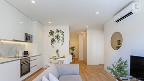 Una sala de estar moderna con un sofá, un televisor y un comedor con mesa y sillas.