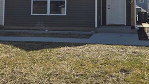 A two-story house with a dark brown exterior, a white door, and a small window. - The Benjamin House, Quality and Comfortable Townhouse with small town feel (Hallsville)