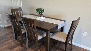 A dining table with four chairs, a small plant, and a white table runner. - The Benjamin House, Quality and Comfortable Townhouse with small town feel (Hallsville)