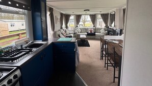 A compact RV interior with a kitchenette, a sofa, and a dining area. - No 38 Heilan Hoose at Three Lochs Newton Stewart (Newton Stewart)