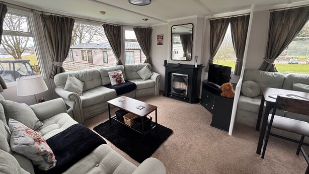 A cozy living room with a fireplace, two sofas, a coffee table, and a TV. - No 38 Heilan Hoose at Three Lochs Newton Stewart (Newton Stewart)