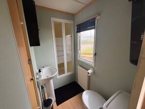 A compact bathroom with a toilet, sink, and window. - No 38 Heilan Hoose at Three Lochs Newton Stewart (Newton Stewart)
