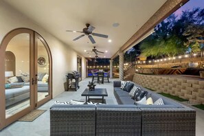 Ein möblierter Patio-Bereich mit einer Couch, Tischen, Deckenventilatoren und Blick ins Freie.