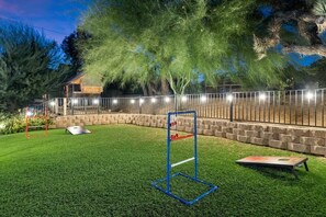 A well-lit outdoor area with a lawn, a metal fence, and a wooden structure in the background.