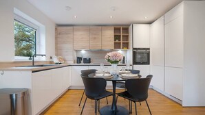 A modern kitchen with a dining area, wooden cabinets, and a built-in oven.